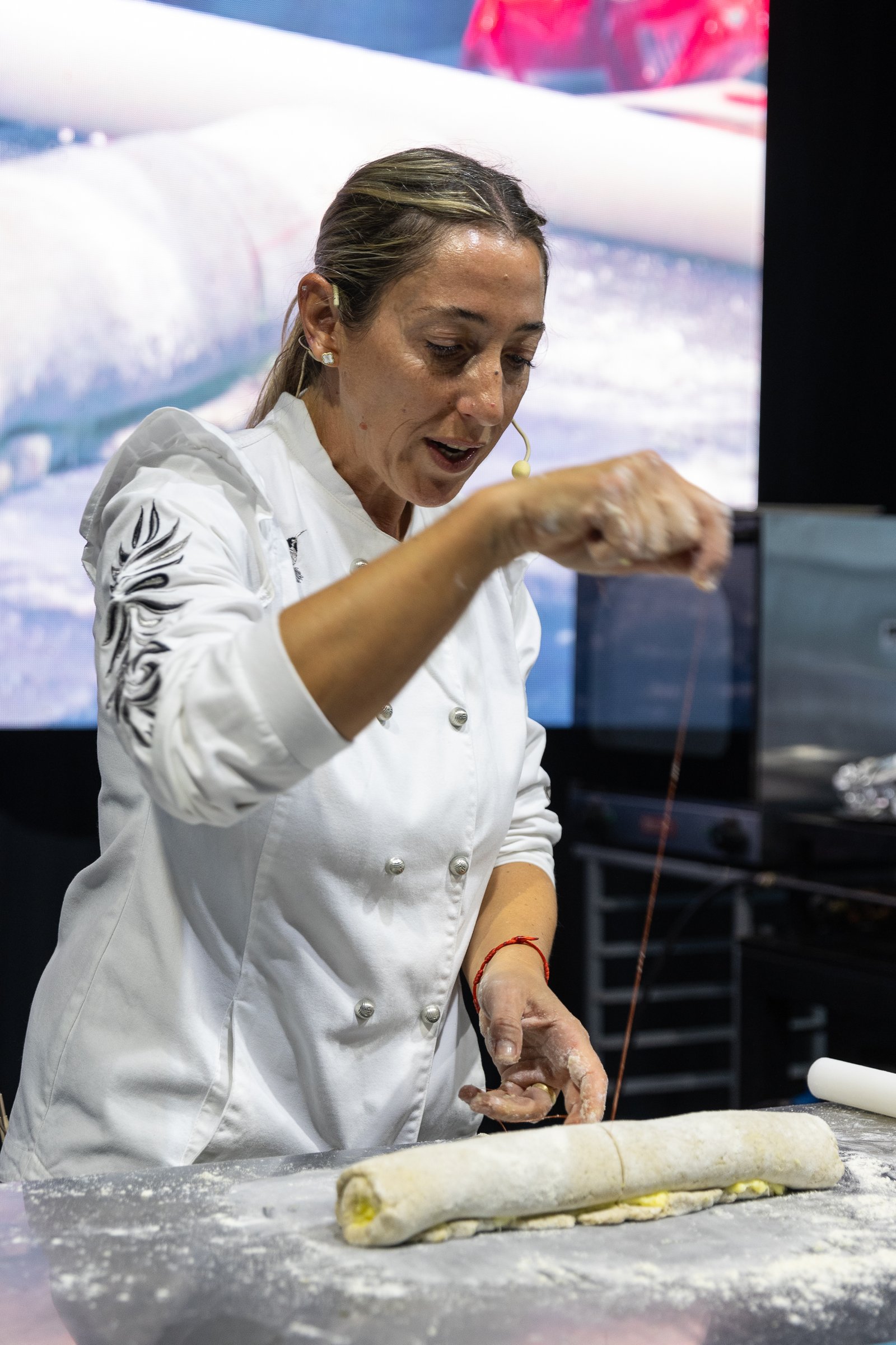 Ale Temporini estirando una masa rellena en la mesada del escenario