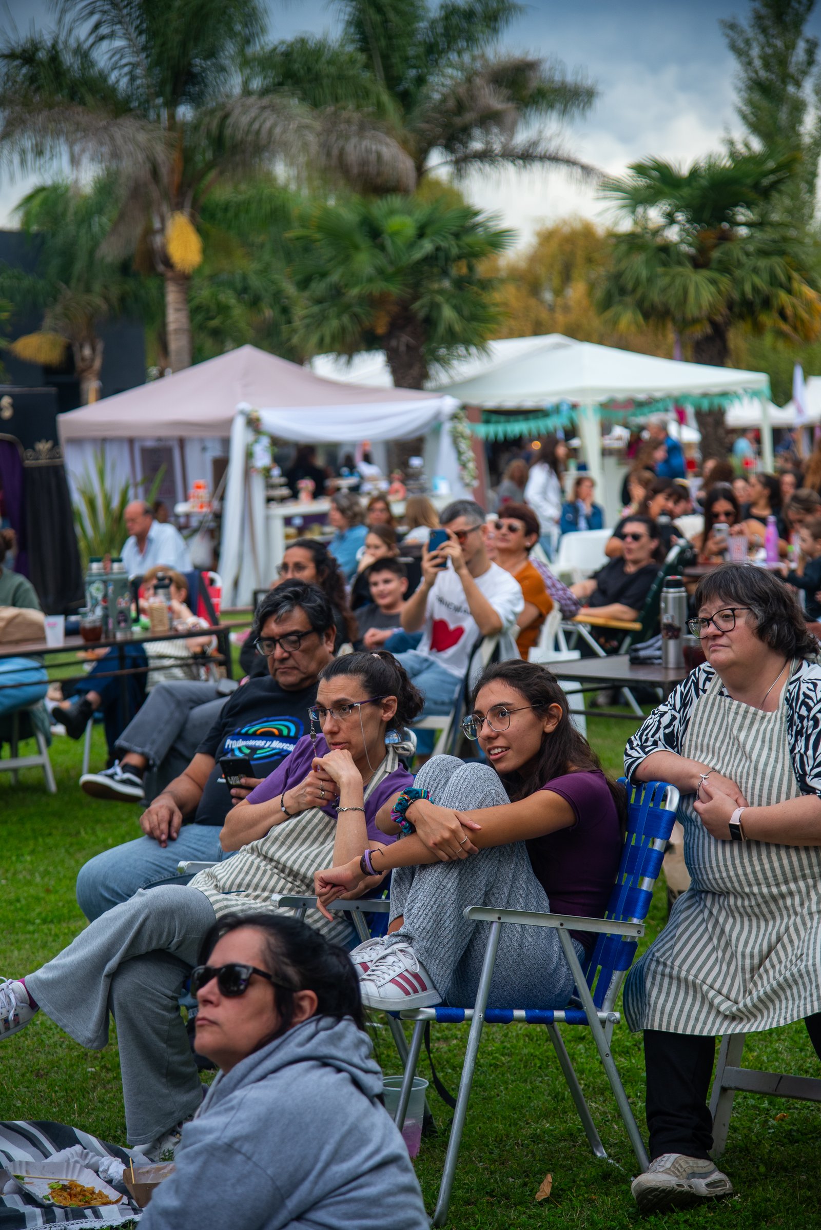 Público sentado en sillas de plástico mirando un espectáculo en vivo