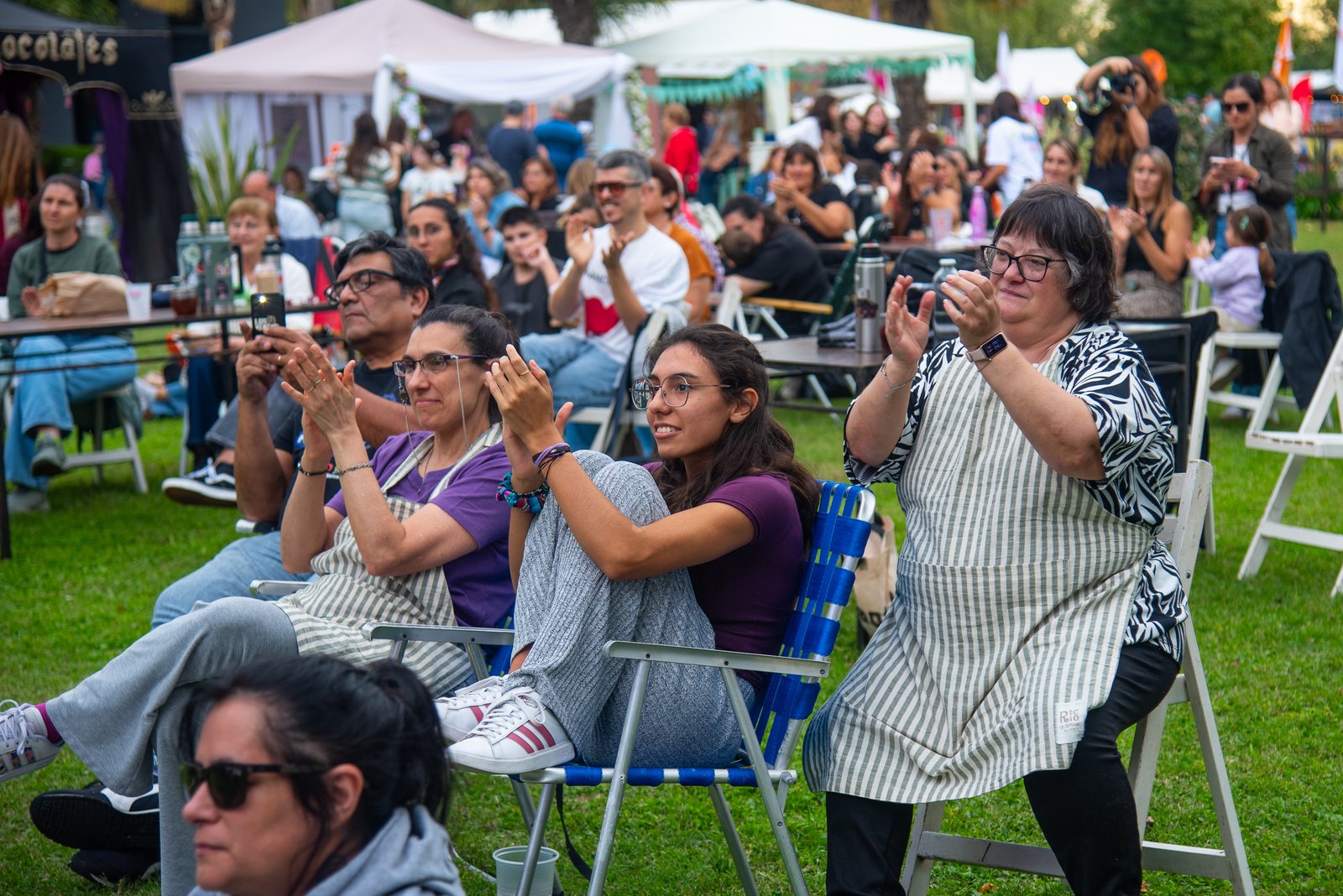 Público aplaudiendo con delantales de cocina puestos durante una demostración