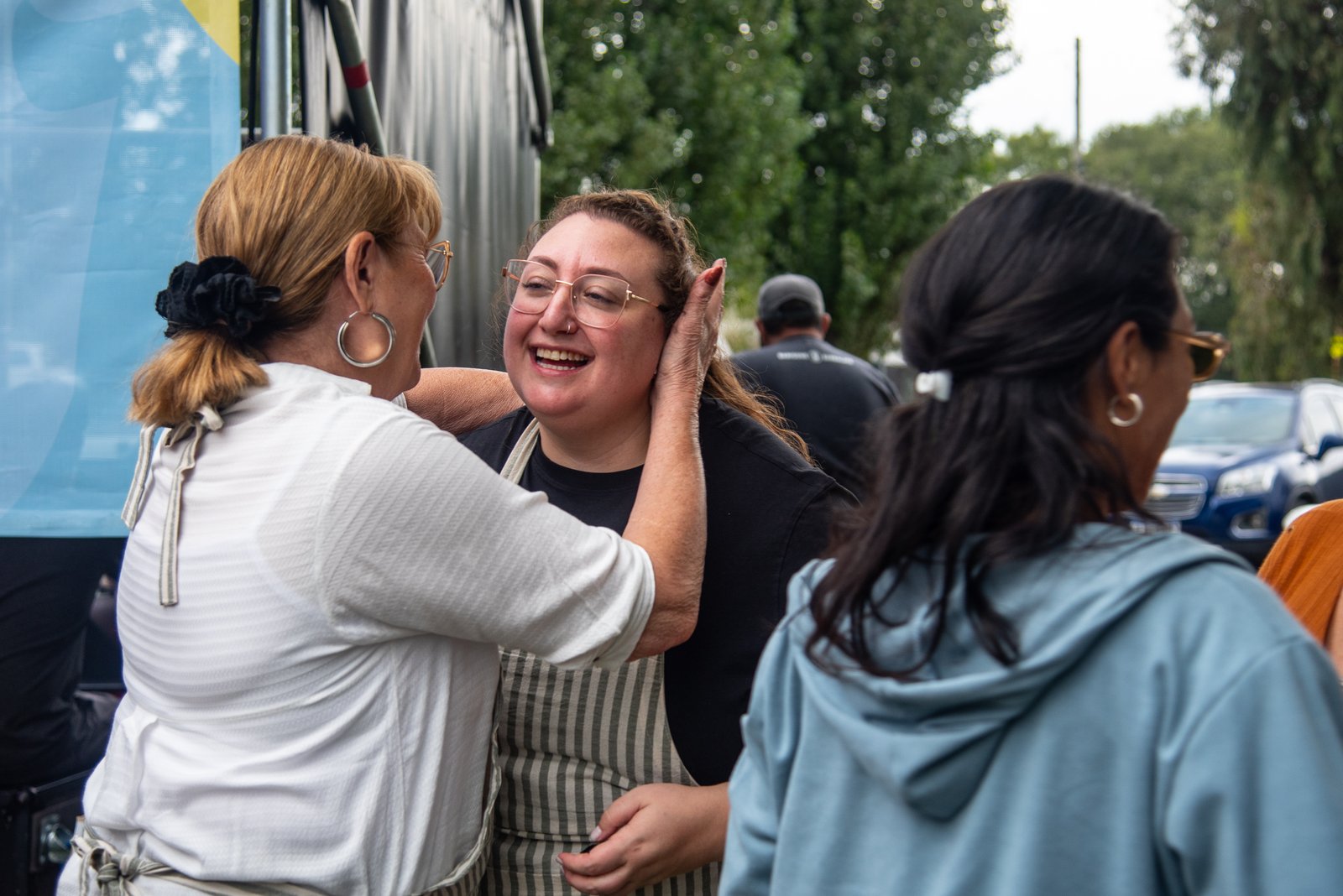 Dos mujeres abrazándose y riendo junto a un escenario