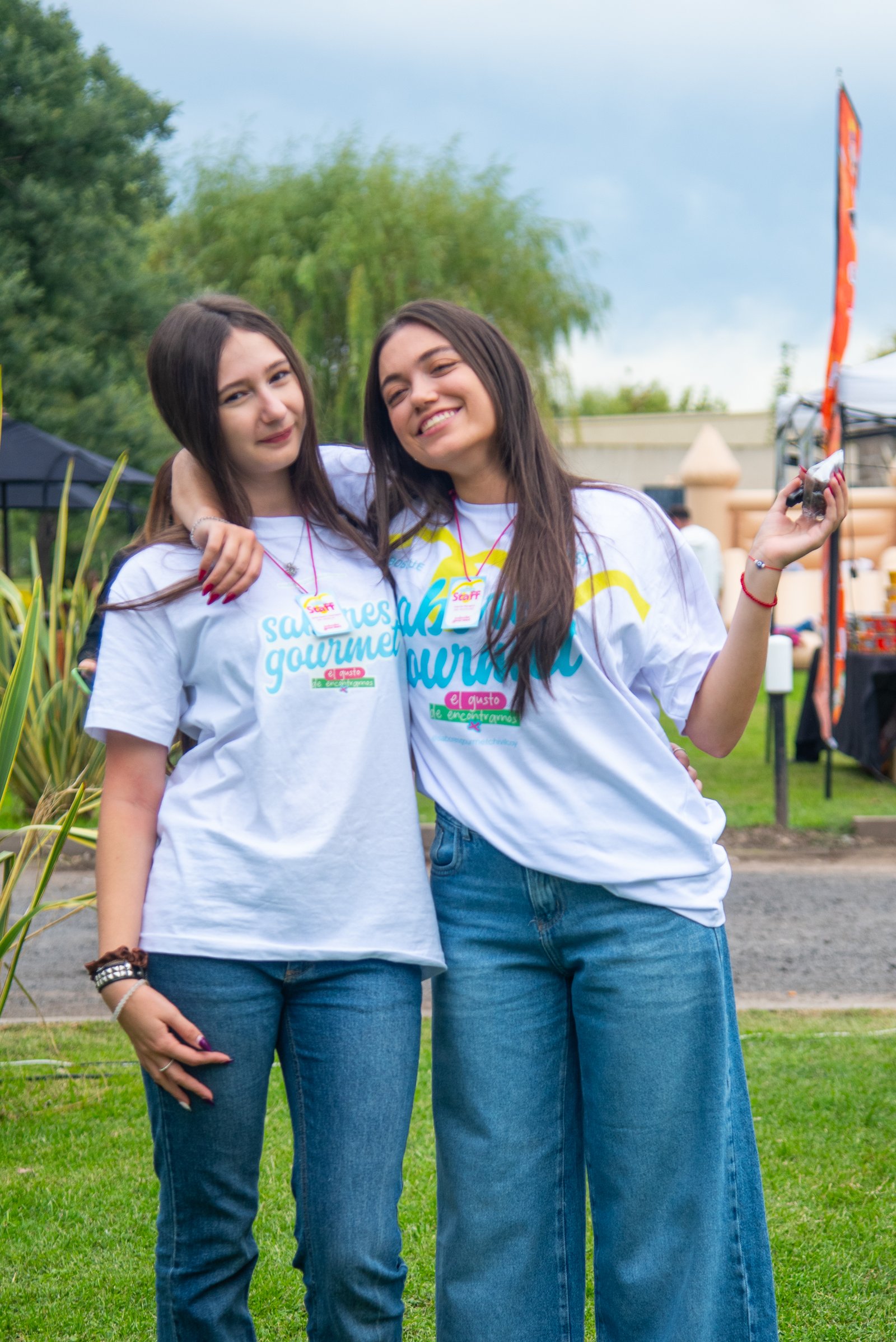 Dos chicas del staff posando abrazadas con las remeras de Sabores Gourmet