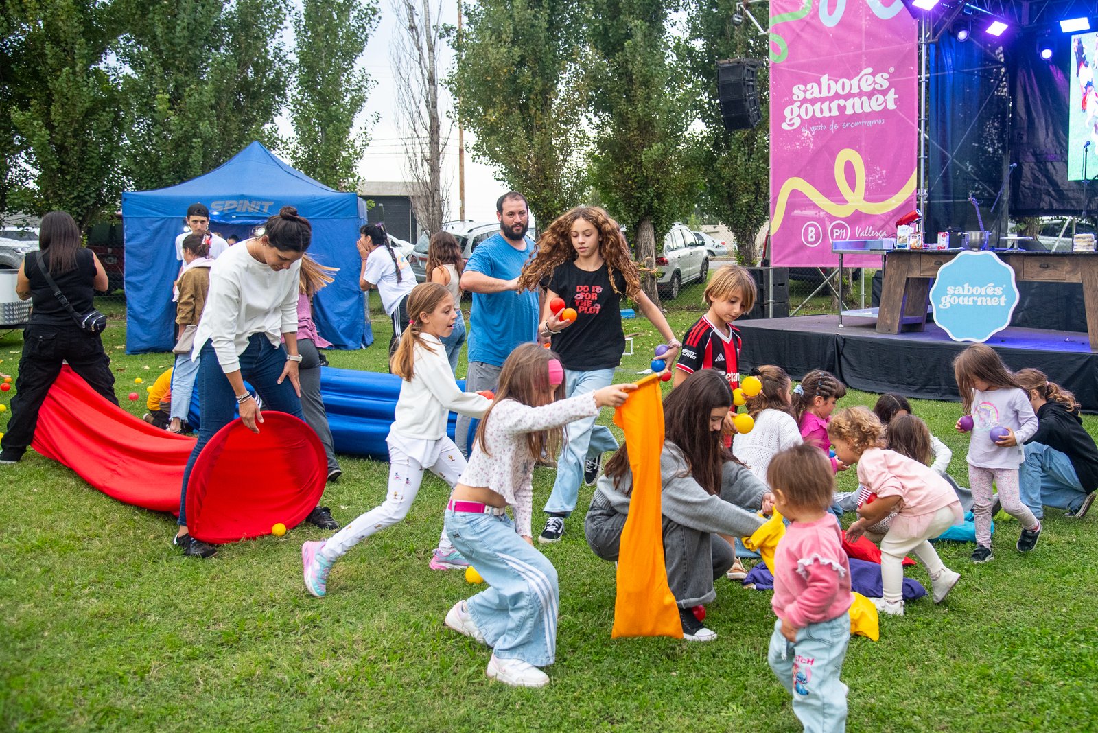 Chicos jugando con una tela y pelotas de colores frente al escenario