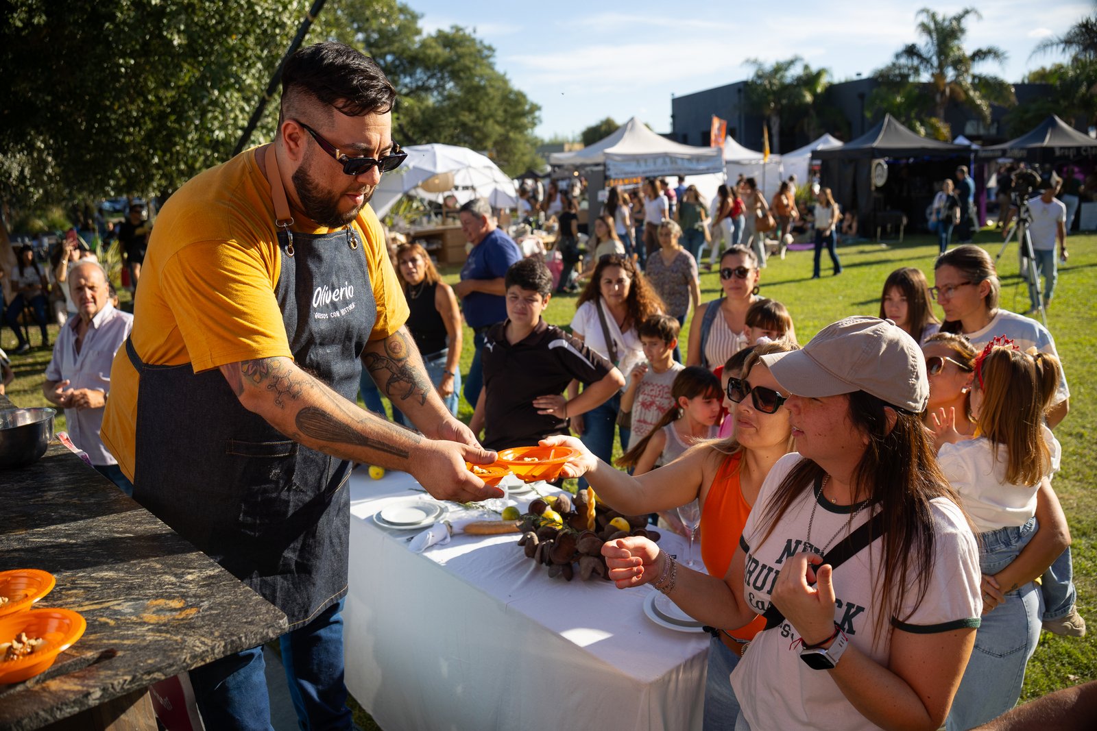 Chef entregando un plato de comida a mujeres que hacen fila frente a su puesto