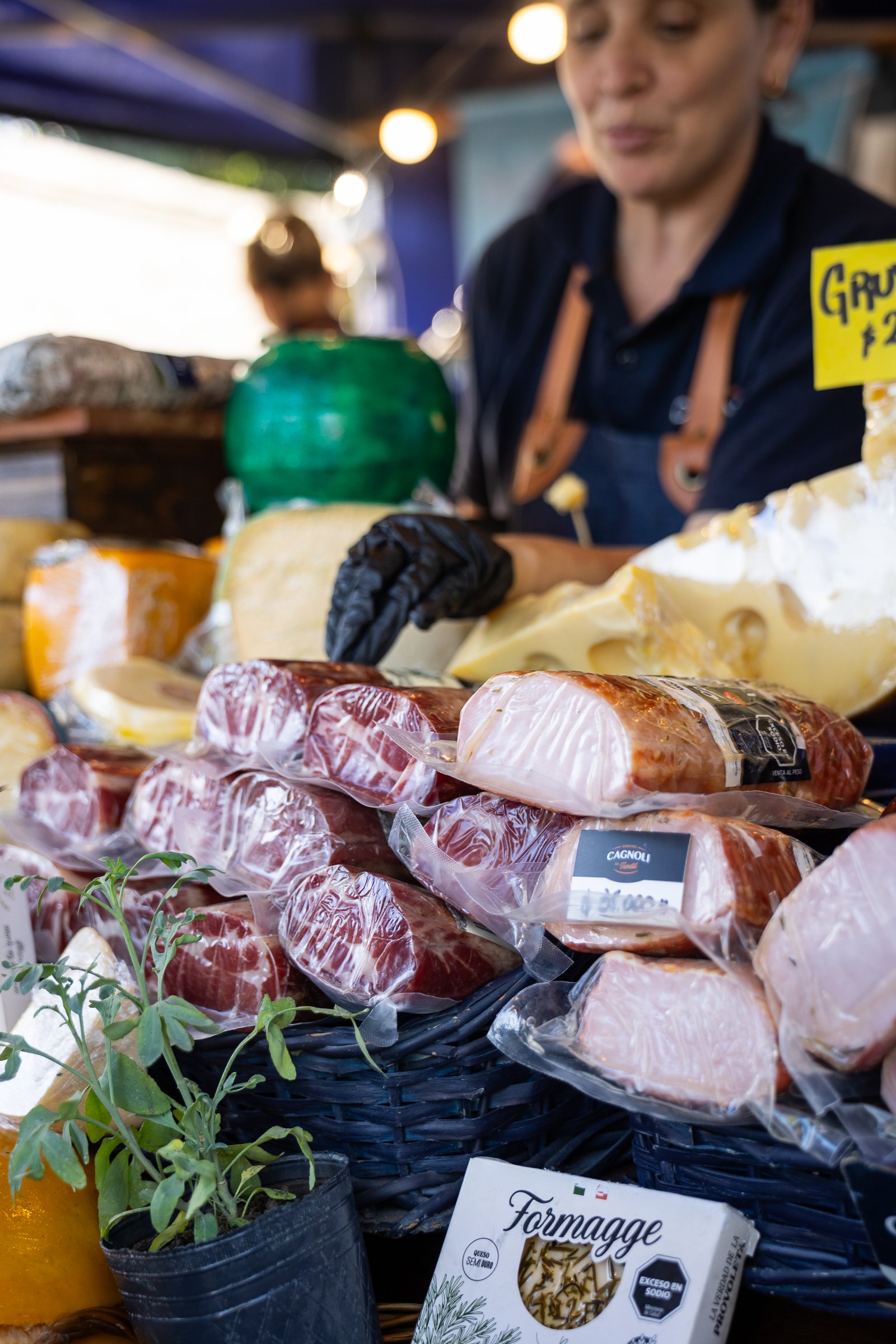 Vendedora acomodando fiambres y quesos envasados en un puesto gourmet