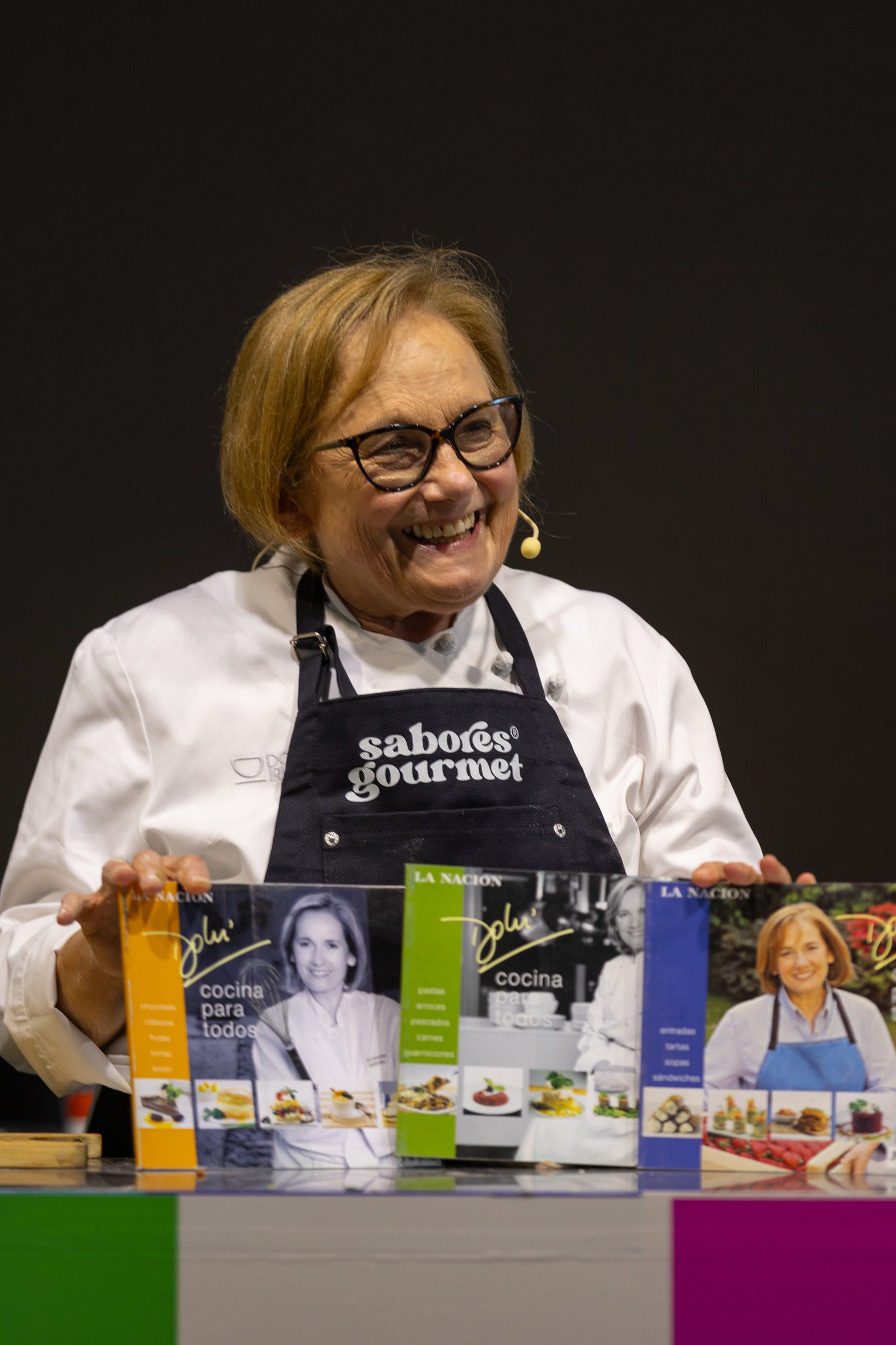 Chef sonriente mostrando sus libros de cocina sobre el escenario